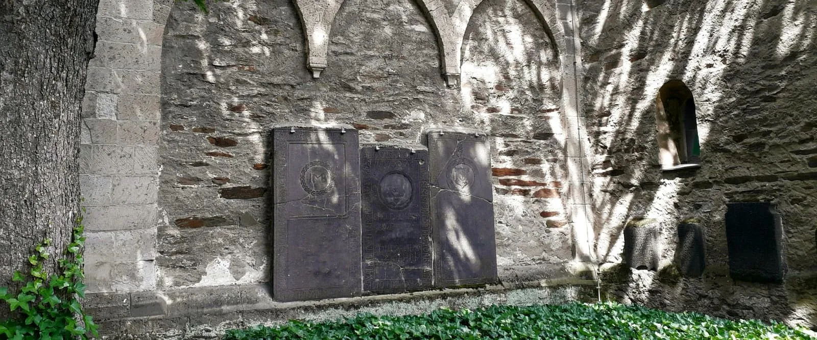 Sechs Grabplatten an der Westseite der Feldkircheder Feldkirche von außen