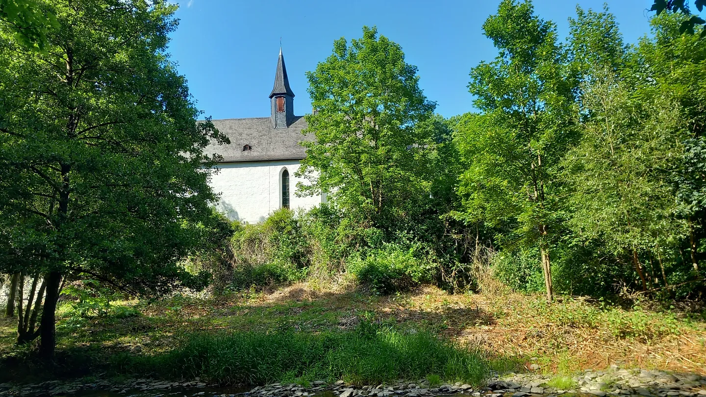 Feldkirche mit Gemeindehaus und Osterglocken im Vordergrund